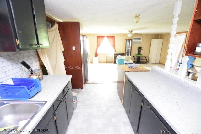 kitchen with light floors, a wall mounted air conditioner, light countertops, and a sink