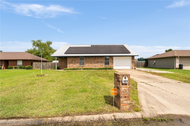 101 Saskatchewan Rd, Roland, OK 74954 - ranch-style home featuring roof mounted solar panels, a garage, concrete driveway, brick siding, and metal roof