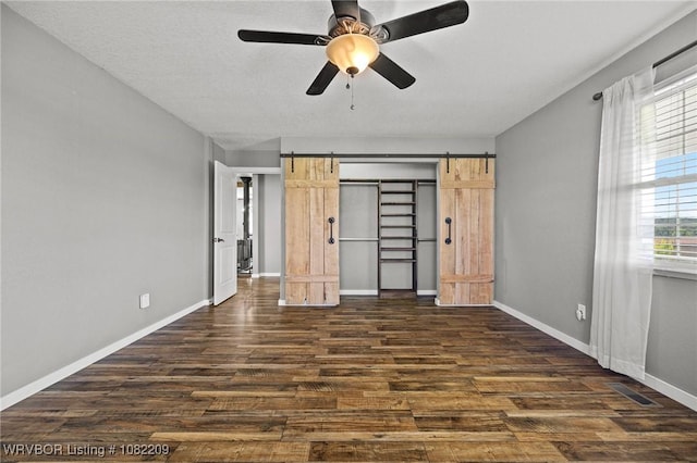 6106 Dean Rd, Alma, AR 72921 - unfurnished bedroom with dark wood-style floors, a ceiling fan, a barn door, and a closet