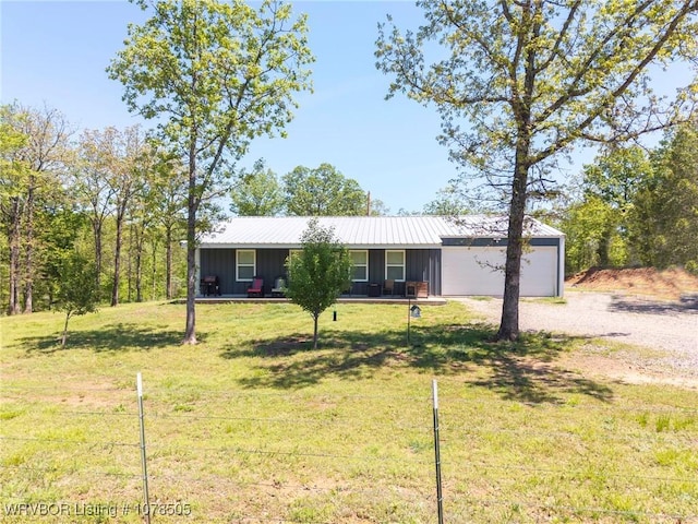 ranch-style home featuring gravel driveway, board and batten siding, a front yard, and an attached garage