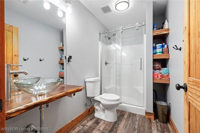 bathroom with sink, hardwood / wood-style floors, a shower with door, and toilet