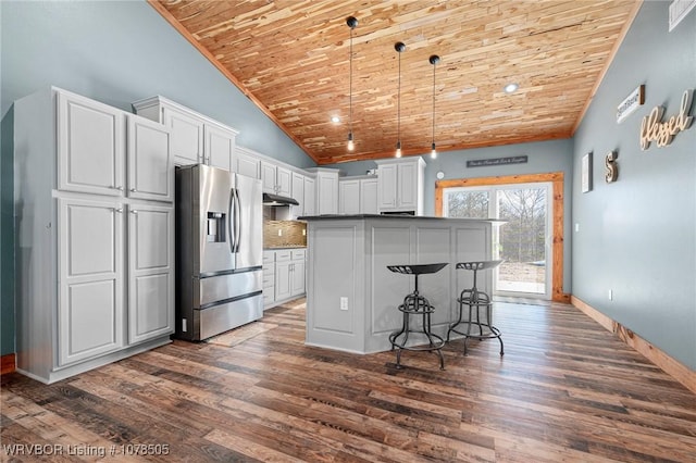 kitchen with stainless steel fridge, decorative light fixtures, white cabinetry, wood ceiling, and decorative backsplash