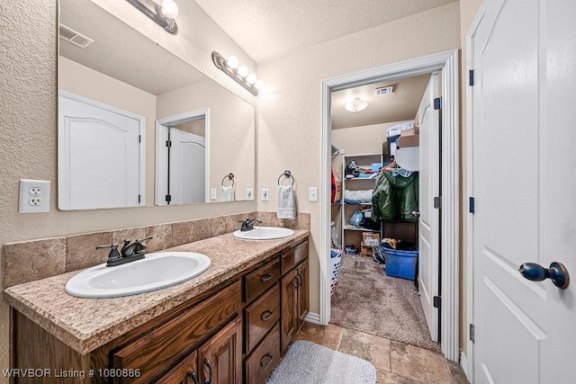 1917 Fisher Rd, Muldrow, OK 74948 - full bath with a textured wall, double vanity, a walk in closet, and stone finish floors