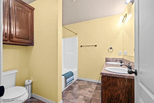 1917 Fisher Rd, Muldrow, OK 74948 - bathroom with toilet, baseboards, stone finish flooring, a textured wall, and double vanity