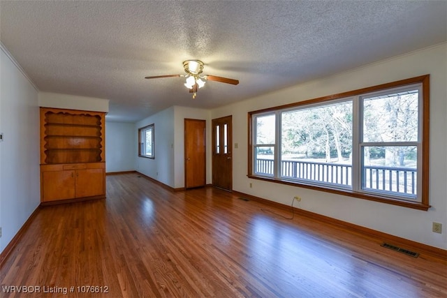 unfurnished living room with ceiling fan, dark hardwood / wood-style flooring, and a textured ceiling