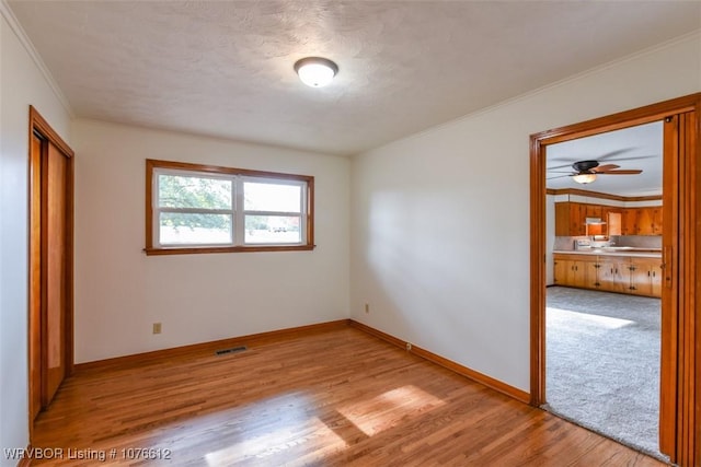 unfurnished bedroom featuring light hardwood / wood-style floors, a textured ceiling, and ornamental molding