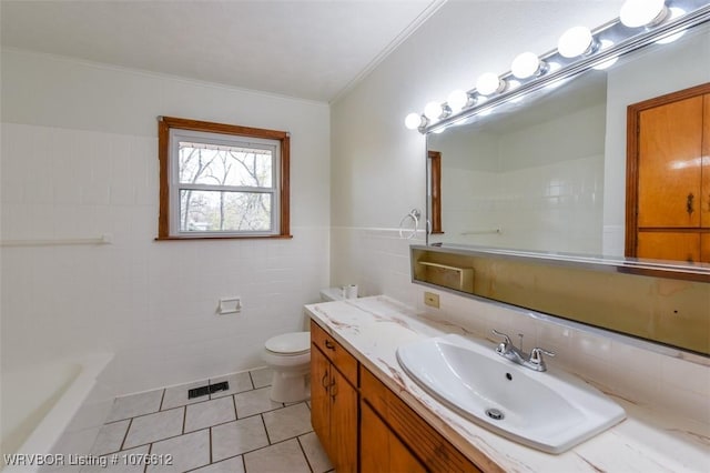 bathroom with tile patterned flooring, toilet, vanity, tile walls, and ornamental molding