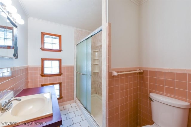 bathroom featuring tile patterned floors, crown molding, tile walls, and toilet