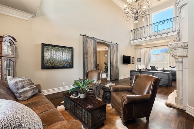 living area featuring wood finished floors, arched walkways, an inviting chandelier, crown molding, and baseboards