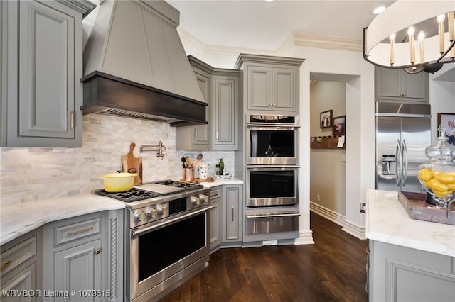 kitchen with premium range hood, gray cabinets, appliances with stainless steel finishes, crown molding, and a warming drawer