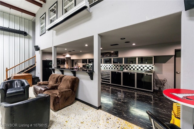 living area with a high ceiling, recessed lighting, and baseboards