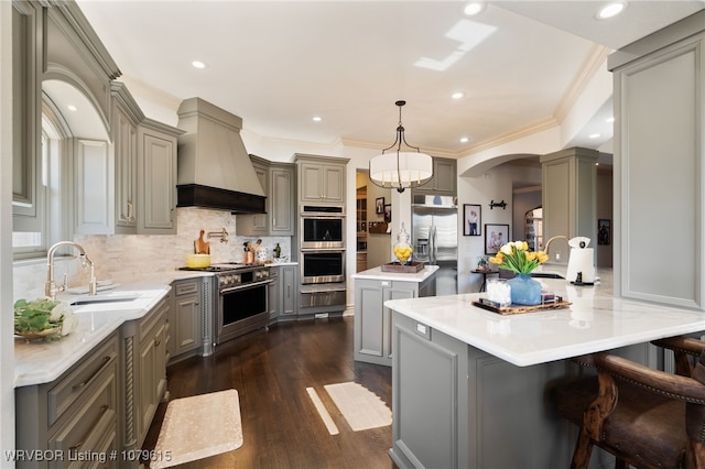 kitchen with a sink, custom exhaust hood, gray cabinetry, and appliances with stainless steel finishes