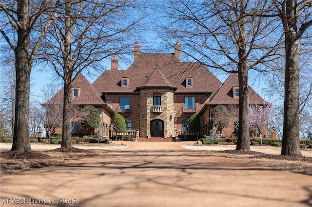 french provincial home with brick siding and a chimney