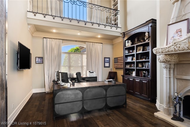 office area featuring dark wood finished floors, baseboards, a towering ceiling, and ornamental molding