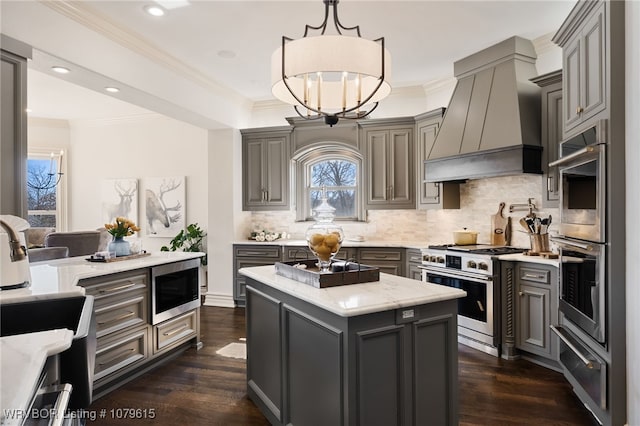 kitchen with a warming drawer, premium range hood, appliances with stainless steel finishes, and gray cabinetry