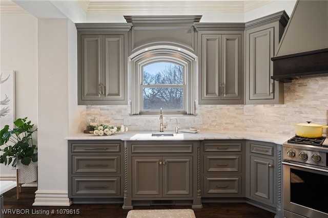 kitchen featuring premium range hood, gray cabinets, a sink, stainless steel range with gas cooktop, and crown molding