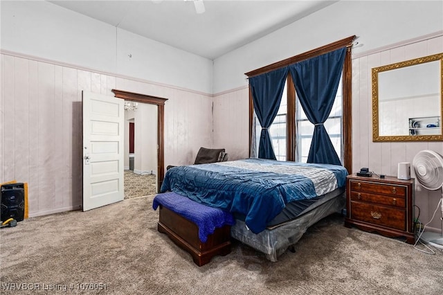 carpeted bedroom featuring ceiling fan and wooden walls