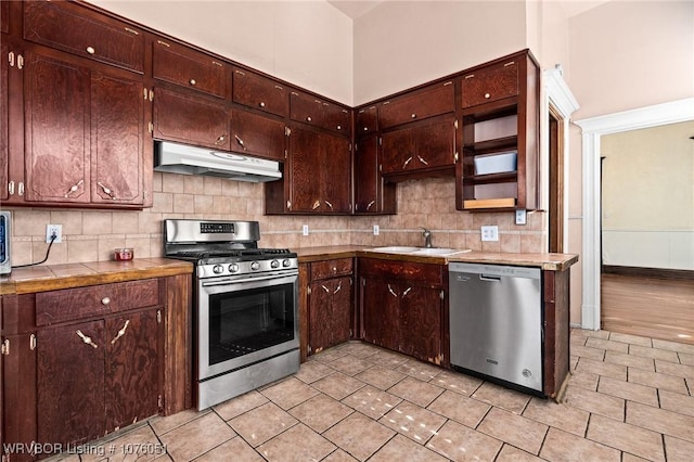 kitchen with appliances with stainless steel finishes, backsplash, dark brown cabinetry, and sink