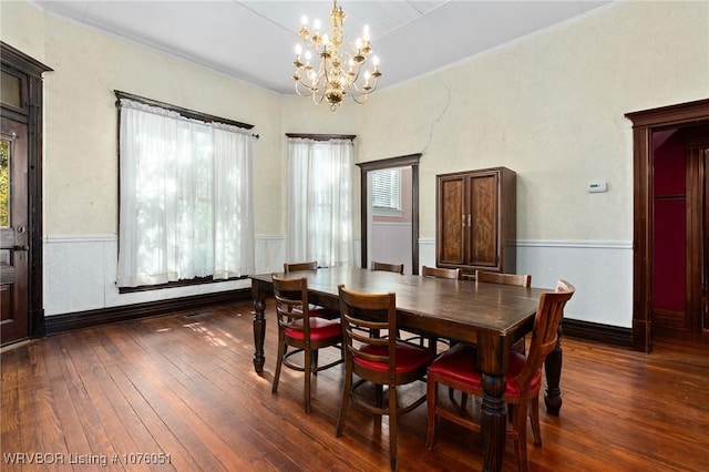 dining room with dark hardwood / wood-style floors and an inviting chandelier