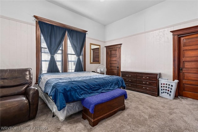 carpeted bedroom featuring wooden walls