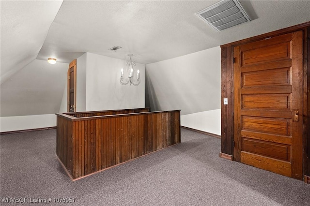 bar featuring dark colored carpet, hanging light fixtures, lofted ceiling, and a notable chandelier