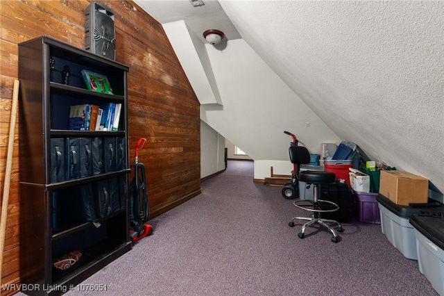 carpeted office space with lofted ceiling, a textured ceiling, and wooden walls