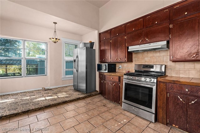 kitchen featuring decorative backsplash, appliances with stainless steel finishes, light tile patterned floors, an inviting chandelier, and hanging light fixtures