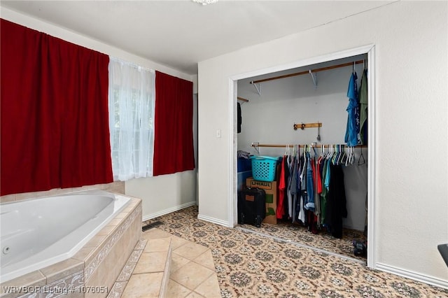 bathroom with tile patterned flooring and a relaxing tiled tub