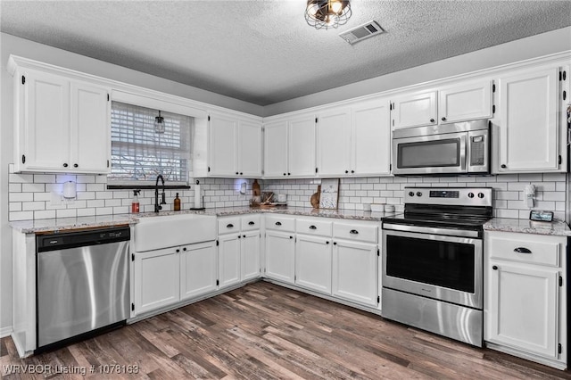 kitchen with light stone countertops, white cabinetry, sink, stainless steel appliances, and a textured ceiling