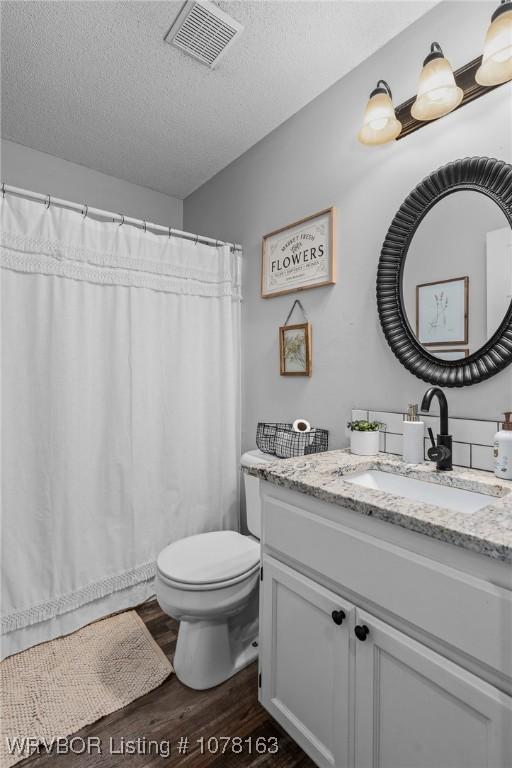 bathroom with toilet, vanity, a textured ceiling, and hardwood / wood-style flooring