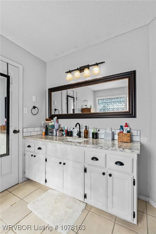 bathroom with tile patterned flooring, vanity, and a textured ceiling