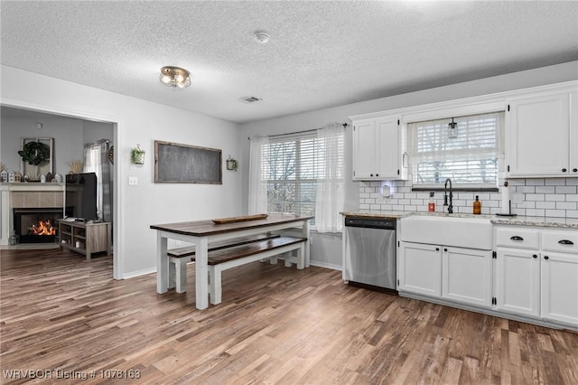 kitchen featuring backsplash, white cabinetry, sink, and stainless steel dishwasher