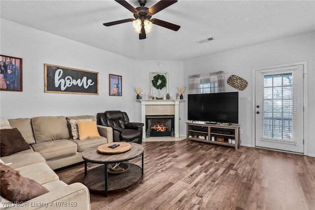 living room with ceiling fan, a fireplace, and hardwood / wood-style flooring