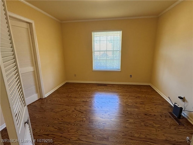 spare room with crown molding, baseboards, and dark wood-style flooring