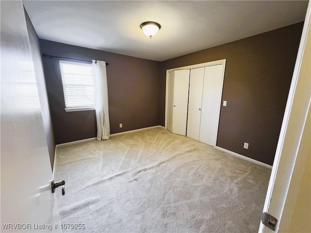 unfurnished bedroom with carpet floors, a closet, and baseboards