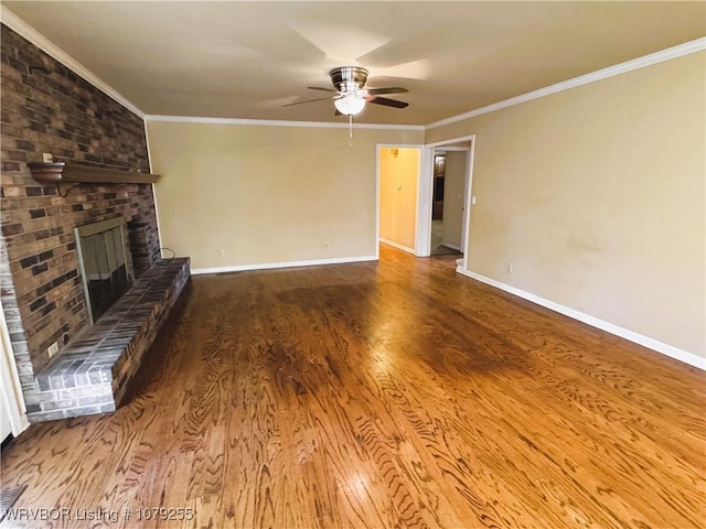 unfurnished living room with baseboards, a brick fireplace, wood finished floors, and crown molding