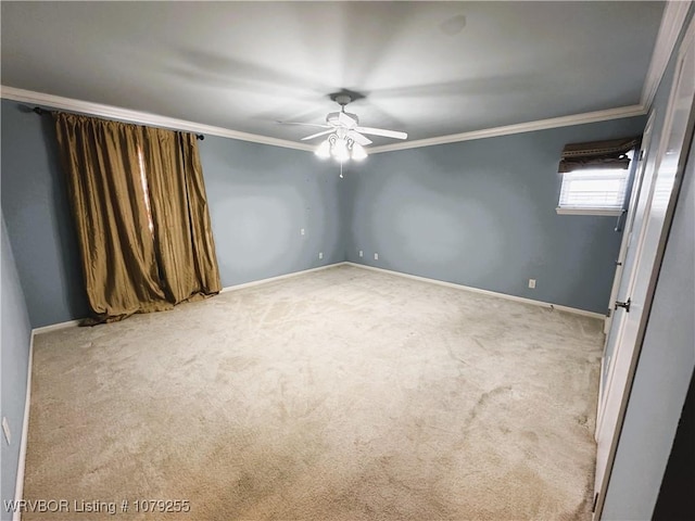 carpeted empty room with ornamental molding, baseboards, and a ceiling fan