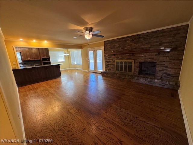 unfurnished living room featuring ceiling fan, ornamental molding, a brick fireplace, and wood finished floors