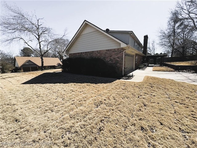 view of side of property featuring concrete driveway, brick siding, and an attached garage