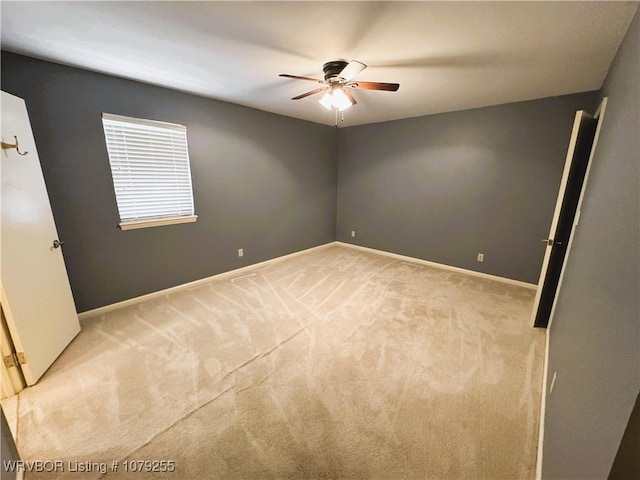 empty room with carpet, a ceiling fan, and baseboards