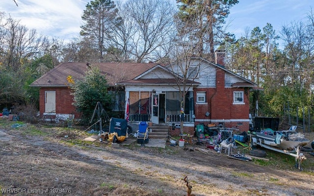 bungalow featuring brick siding and a chimney