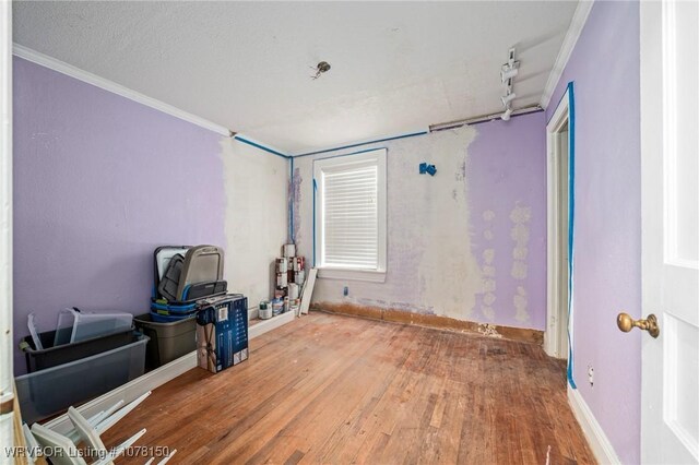 interior space featuring hardwood / wood-style flooring, ornamental molding, and a textured ceiling