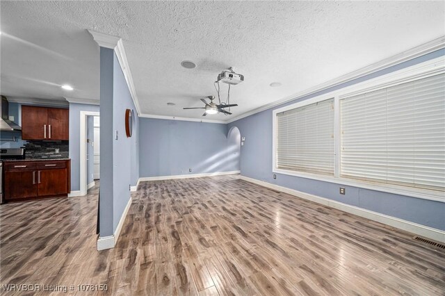 unfurnished living room with ceiling fan, wood-type flooring, ornamental molding, and a textured ceiling