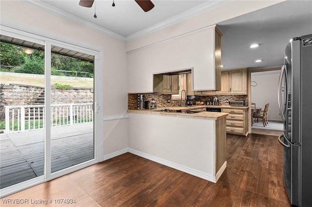 kitchen featuring kitchen peninsula, stainless steel fridge, decorative backsplash, ceiling fan, and crown molding