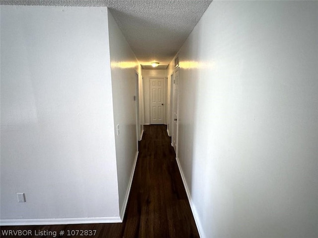 hall featuring a textured ceiling and dark hardwood / wood-style floors