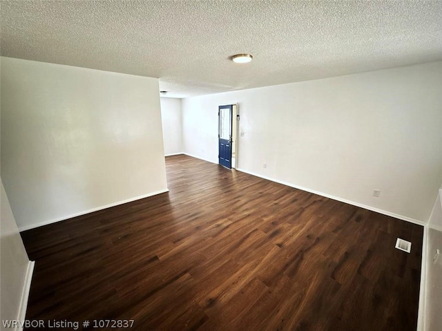 spare room featuring a textured ceiling and dark hardwood / wood-style flooring