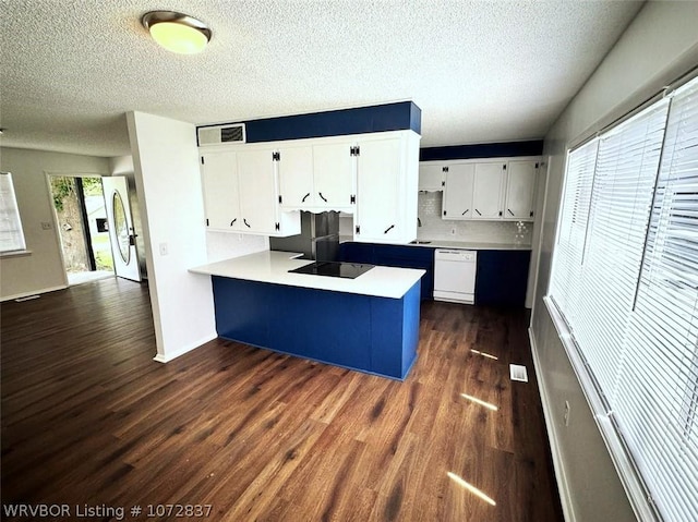 kitchen featuring white appliances, kitchen peninsula, dark hardwood / wood-style floors, plenty of natural light, and white cabinetry