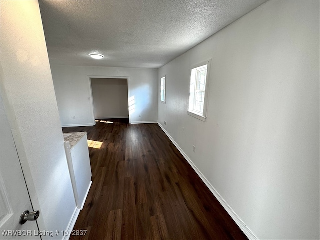 hall featuring a textured ceiling and dark wood-type flooring