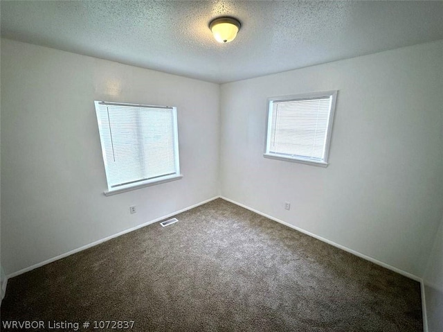 carpeted empty room featuring a textured ceiling