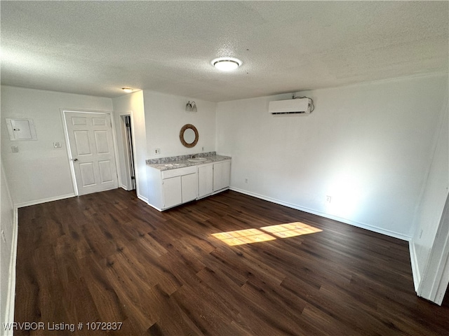 interior space featuring dark hardwood / wood-style floors, a textured ceiling, and a wall unit AC